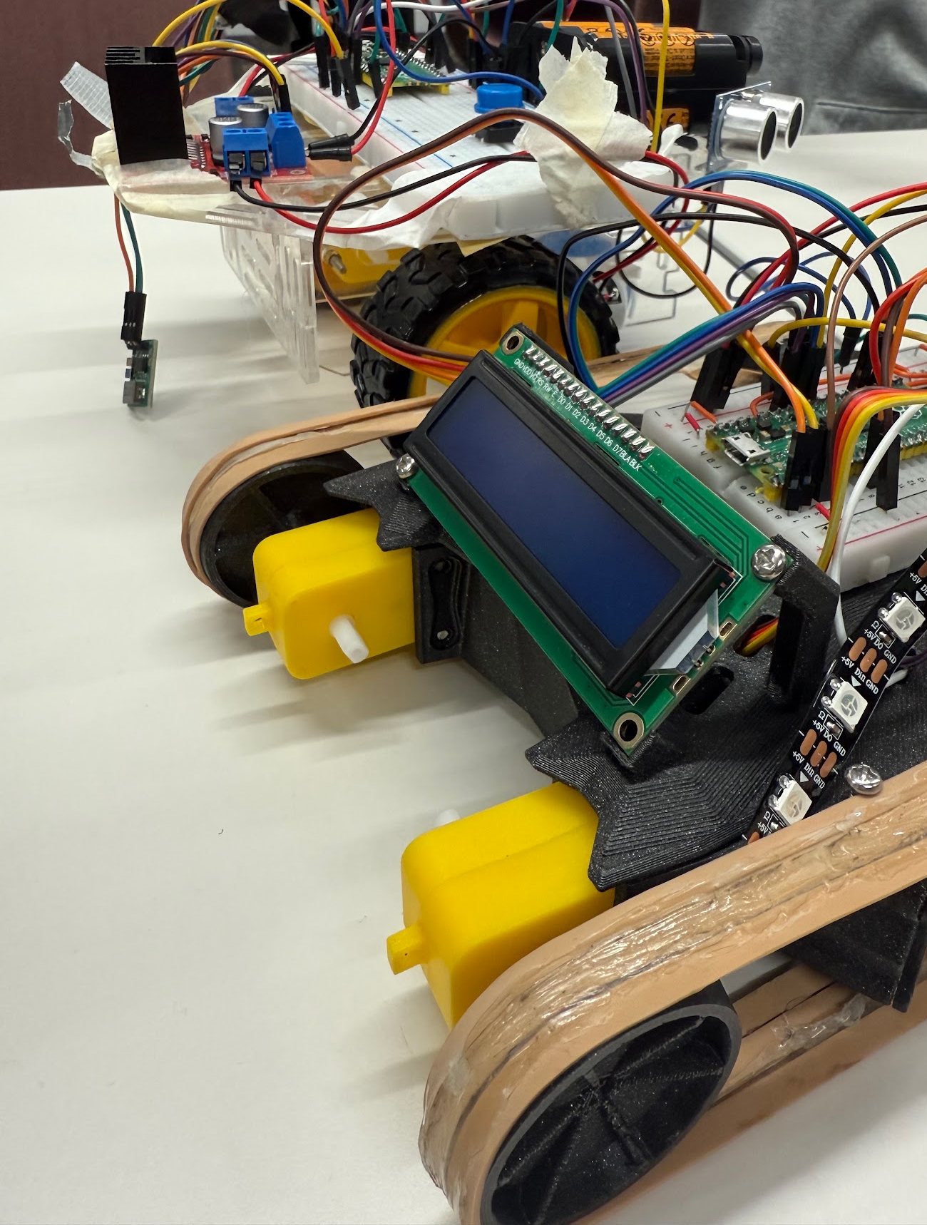 The printed tank-drive robot in the foreground, with the taller class-kit robot on large rubber wheels behind it